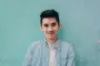 man wearing blue white stripe shirt leaning on the wall